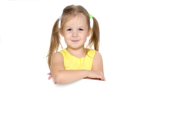A little girl is looking from behind an empty banner. — Stock Photo, Image