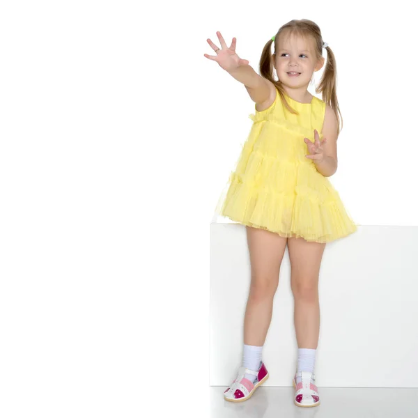 A little girl is looking from behind an empty banner. — Stock Photo, Image