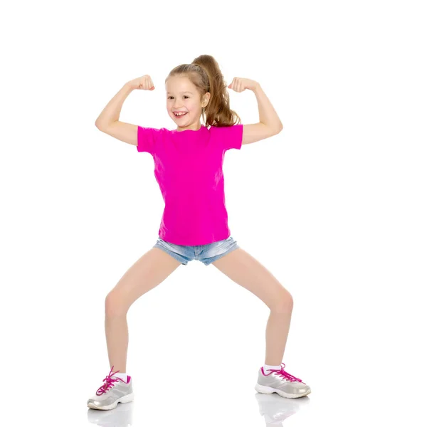 Een klein meisje toont haar spieren. — Stockfoto