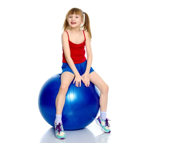 Una niña está saltando en la gran pelota de gimnasia . — Foto de Stock