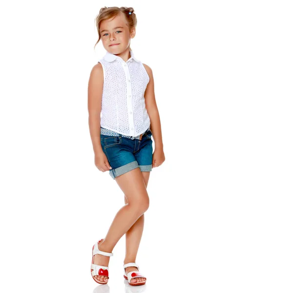 En liten flicka i shorts och en vit skjorta. — Stockfoto