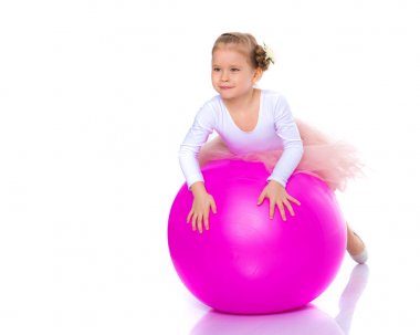 Küçük kız spor yapmak için büyük bir top üzerinde egzersiz yapıyor..