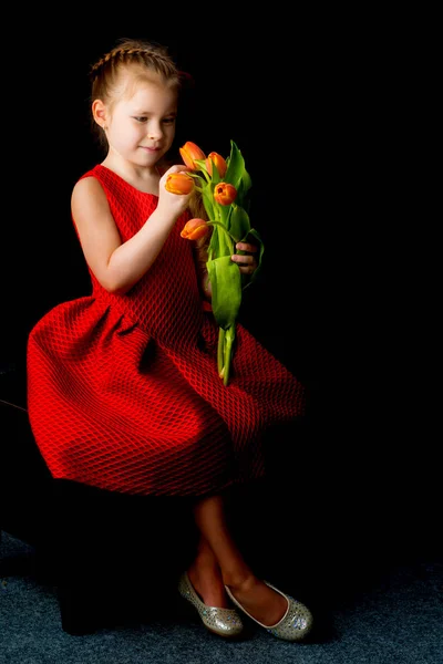 Menina com um buquê de tulipas em um fundo preto . — Fotografia de Stock