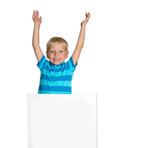 Un niño pequeño está mirando detrás de una pancarta vacía . — Foto de Stock