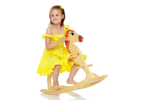 Girl swinging on a wooden horse. — Stock Photo, Image