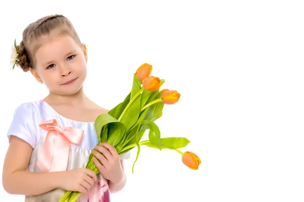 Klein meisje met een boeket tulpen. — Stockfoto