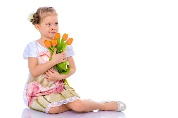 Little girl with bouquet of flowers sits on the floor. — Stock Photo, Image