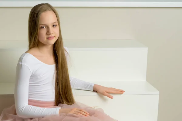 Hermosa niña está sentada en la escalera blanca. — Foto de Stock