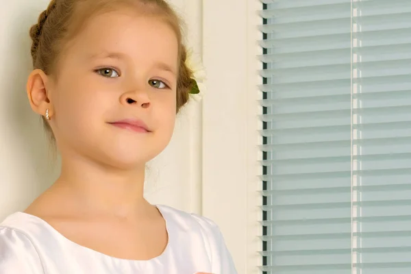 Una bambina è seduta sulla finestra sullo sfondo del — Foto Stock