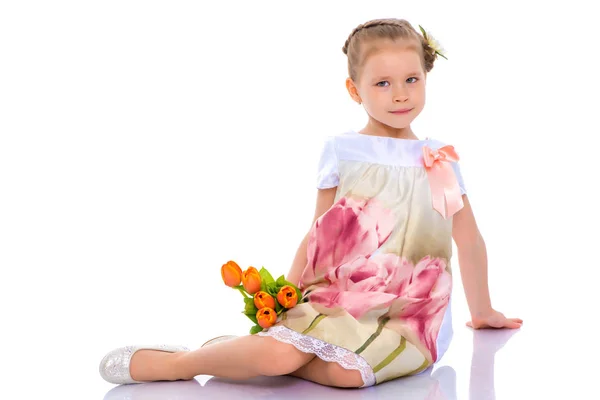 Little girl with bouquet of flowers sits on the floor. — Stock Photo, Image