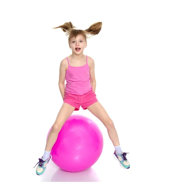 A little girl is jumping on the big gym ball. — Stock Photo, Image