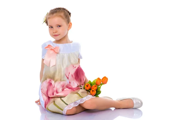 Meisje met boeket bloemen zit op de vloer. — Stockfoto