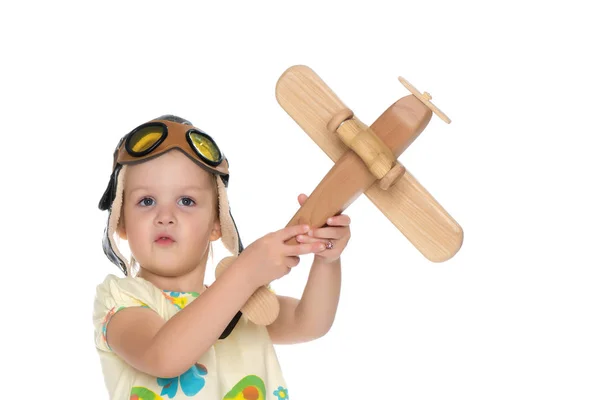 Klein meisje met een houten vliegtuig in haar hand. — Stockfoto