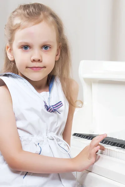 Krásná holčička hraje na bílé klavír. — Stock fotografie