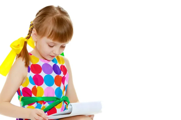 Een klein meisje leest het boekje. — Stockfoto