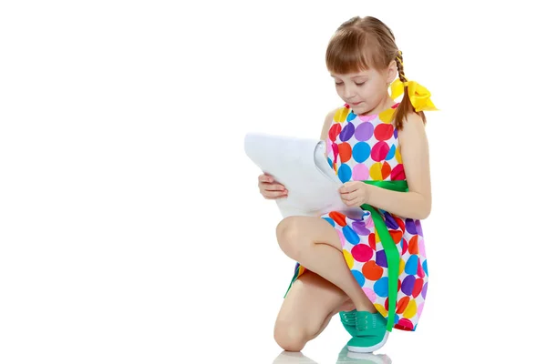Ein kleines Mädchen liest das Büchlein. — Stockfoto