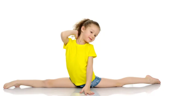 Den lilla gymnasten utför ett akrobatiskt element på golvet. — Stockfoto