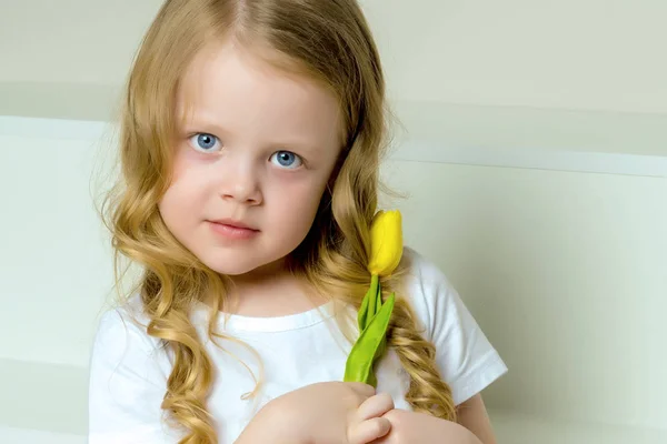 A little girl with a bouquet of tulips is sitting on the stairs. — Stock Photo, Image