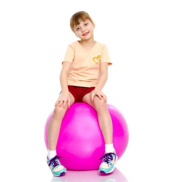 Bambina che fa esercizi su una palla grande per idoneità. — Foto Stock