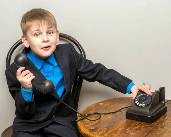 Den lille dreng ringer til den gamle telefon . - Stock-foto