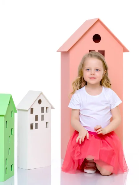 Little girl is playing with wooden houses. — Stock Photo, Image