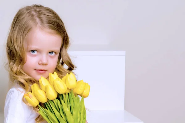 Klein meisje met een boeket tulpen. — Stockfoto