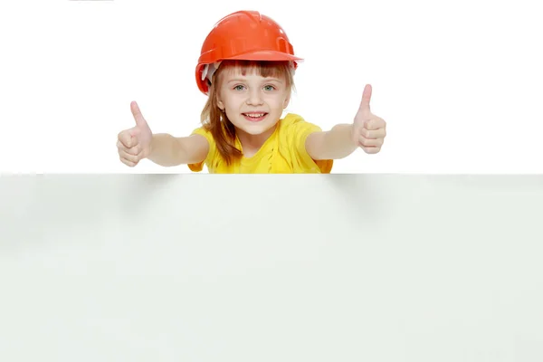 Chica en un casco de construcción asoma por detrás de una valla publicitaria . —  Fotos de Stock