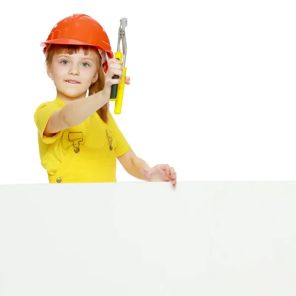 Chica en un casco de construcción asoma por detrás de una valla publicitaria . —  Fotos de Stock