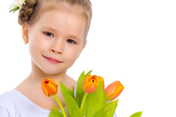 Klein meisje met een boeket tulpen. — Stockfoto