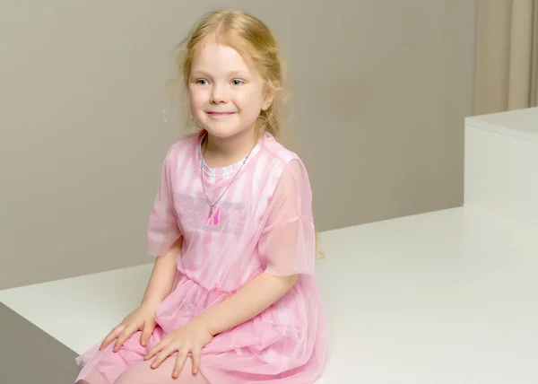 Beautiful little girl is sitting on the white staircase. — Stock Photo, Image