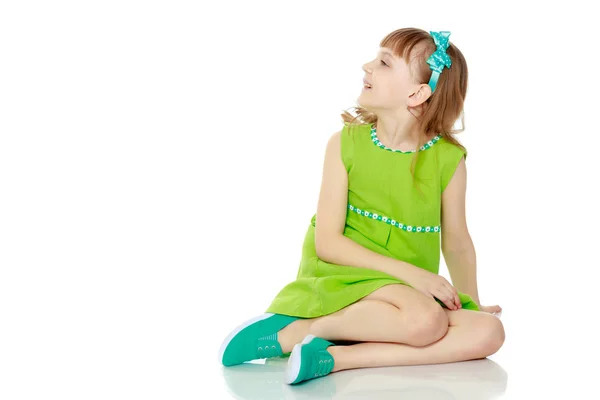 The girl is sitting on the floor with her hands clasped around h — Stock Photo, Image