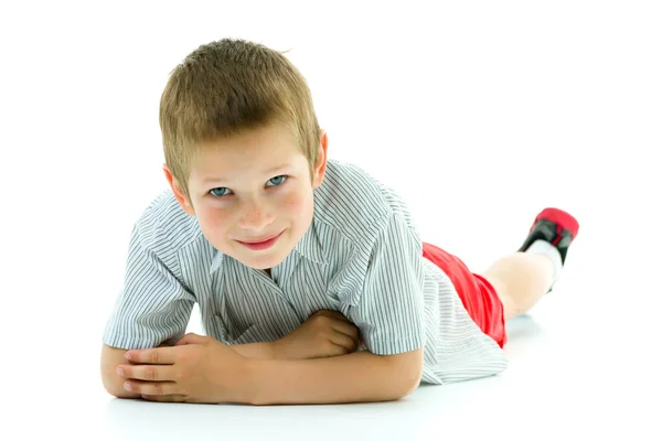 Gelukkig jongetje is liggend op de vloer in de studio. — Stockfoto