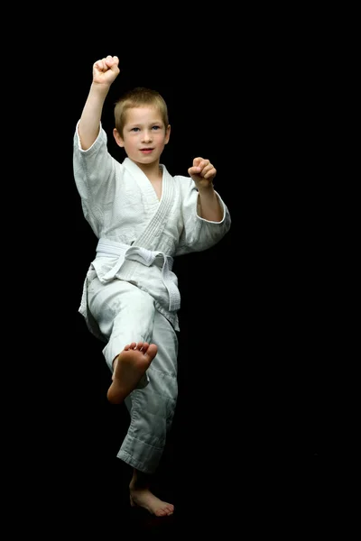 Маленький мальчик в белом кимоно выполняет удары — стоковое фото
