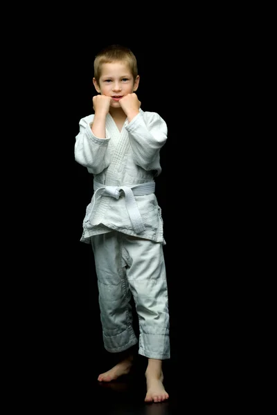 Маленький мальчик в белом кимоно выполняет удары — стоковое фото