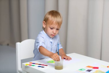 Şirin küçük çocuk hesabı öderken suluboya boyayla resim yapıyor.