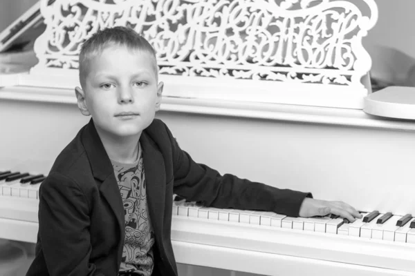 Liten pojke i studio nära vit piano. — Stockfoto