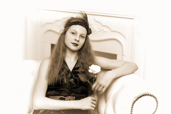 Chica adolescente sentada en el sofá sosteniendo una flor en su mano . —  Fotos de Stock