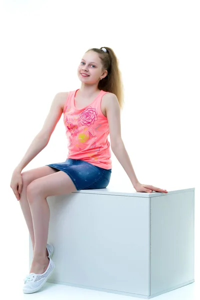 Sevimli genç kız beyaz küp stüdyoda oturur — Stok fotoğraf