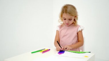 Küçük bir kız masada çizim.