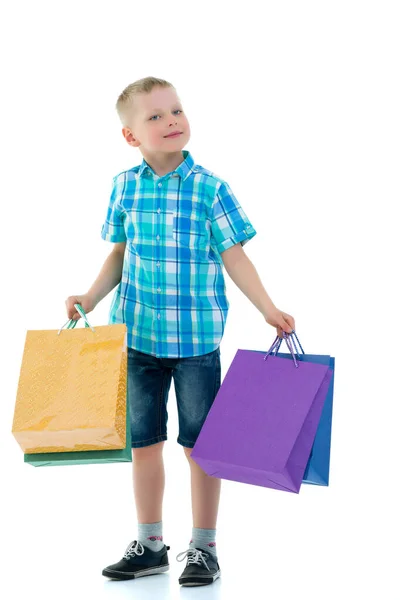 Little boy waving multicolored paper bags. He goes shopping — Stock Photo, Image