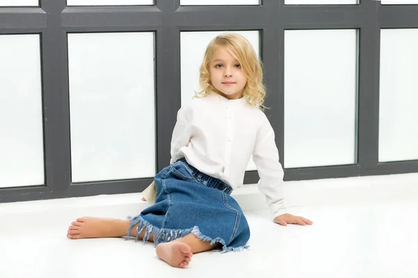 Klein meisje zittend op de vloer bij het raam — Stockfoto