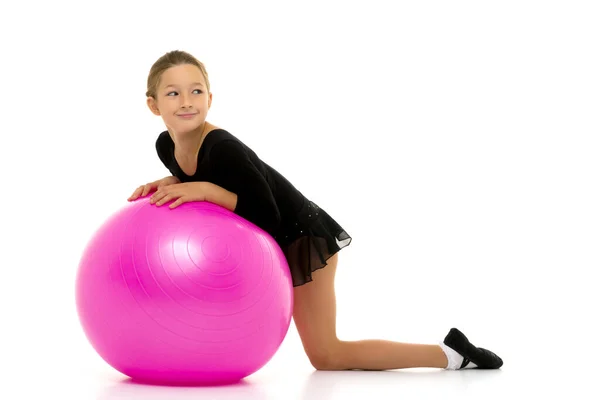 Kleines Mädchen macht Übungen auf einem großen Ball für Fitness. — Stockfoto