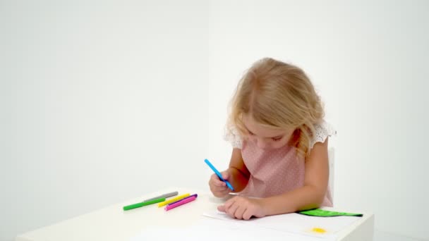 Ein kleines Mädchen zeichnet am Tisch. — Stockvideo