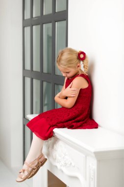 Büyük bir stüdyoda büyük bir panoramik pencerenin yanında küçük bir kız..