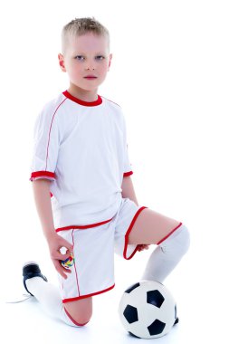 Saf beyaz giyen küçük bir çocuk t-shirt ile bir socc oynuyor