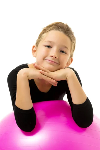 Kleines Mädchen macht Übungen auf einem großen Ball für Fitness. — Stockfoto