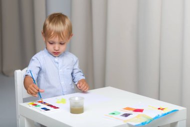 Şirin küçük çocuk hesabı öderken suluboya boyayla resim yapıyor.