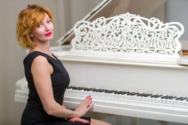 Güzel genç kadının yanına Beyaz kuyruklu piyano.