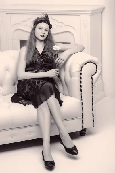 Hermosa joven sentada en el sofá junto a la chimenea —  Fotos de Stock