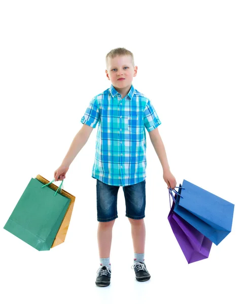 Küçük çocuk çok renkli kağıt torbalar sallıyor. Alışverişe gidiyor. — Stok fotoğraf